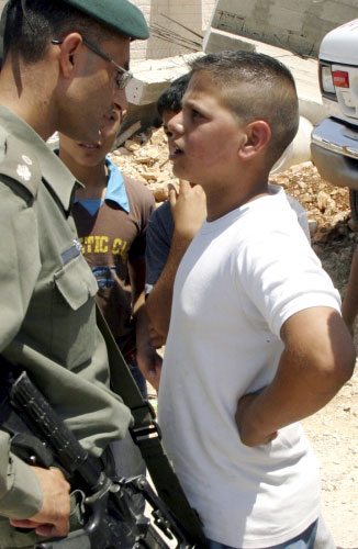 فتى فلسطيني يواجه جندياً إسرائيلياً أثناء هدم منزل على حدود القدس المحتلّة أمس (محفوظ أبو تلرك - رويترز)
