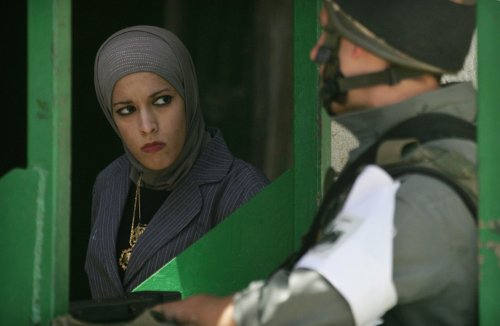 فلسطينية تمر أمام جندي اسرائيلي في الخليل أمس (نايف هشلمون - رويترز)