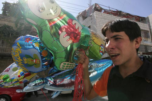 فتى فلسطيني يعرض ألعاباً للبيع استعداداً لعيد الفطر في الخليل أمس (حازم بدر - أ ف ب)