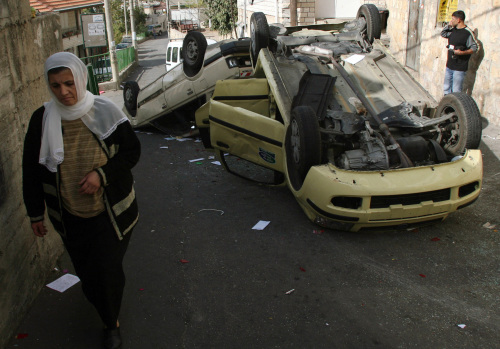 فلسطينية بالقرب من سيارتين محطمتين في قرية البقيعة أمس (أحمد غربلي ــ أ ب)