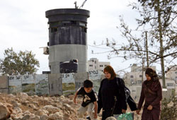 عائلة فلسطينية تمرّ بجانب مستوطنة «كريات أربع» في الخليل أول من أمس (حازم بدر ـ أ ف ب)