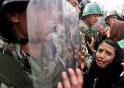 عناصر من الشرطة المصريّة يواجهون متظاهرين فلسطينيين عند معبر رفح الحدودي أمس (علي علي ـ إي بي أي)