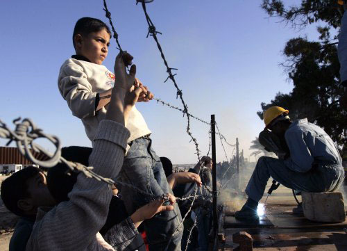 فلسطيني يراقب عمّالاً مصريّين يقفلون الحدود مع غزّة يوم الجمعة الماضي (إبراهيم أبو مصطفى ـ رويترز)