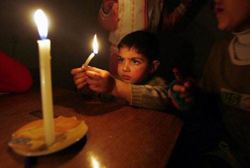 طفل فلسطيني يضيء شمعة خلال انقطاع للتيّار الكهربائي في غزة أمس (سهيب سالم ـ رويترز)
