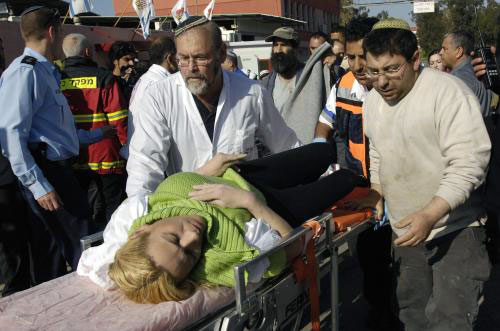 مسعفون إسرائيليّون ينقلون امرأة مصابة جراء سقوط صاروخ على معمل في سديروت أمس (عمير كوهين ـ رويترز)