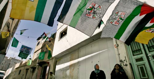 تراقبان أعلام الفصائل في أحد احياء المخيّم (أ ب)