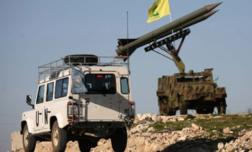آلية تابعة لـ«اليونيفيل» أمام مجسّم لمنصة صواريخ يعلوها علم حزب الله في جنوب لبنان (حسن بحسون)