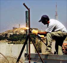عامل إسرائيلي يصلح السياج عند الجانب الإسرائيلي من الخط الأزرق أمس (ا ف ب)