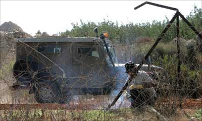 عربة عسكرية إسرائيلية قرب عامل يصلح السياج الحدودي جنوب لبنان امس (أ ب)