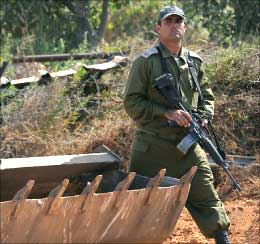 جندي إسرائيلي يسير قرب جرافة عند الحدود اللبنانية أمس (أ ب)