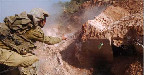 جندي إسرائيلي يلقي قنبلة دخانية داخل خندق تابع لحزب الله في صورة نشرتها وزارة الدفاع الإسرائيلية أمس (رويترز) 