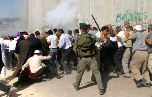 جندي إسرائيلي يهاجم فلسطينيين يحاولون العبور إلى القدس المحتلة أمس (أ ف ب)