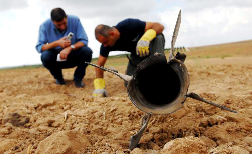 خبيران إسرائيليان يتفحصان صاروخاً سقط على سيدروت أمس (رويترز)