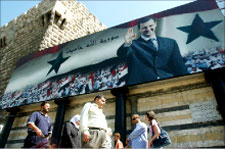 سوريون يسيرون في دمشق تحت صورة للرئيس السوري بشار الأسد (أ ب)