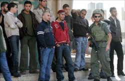 جندي إسرائيلي يراقب معتقلين في الخليل أمس (إي بي إي)