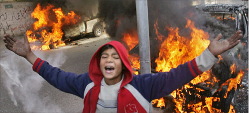 فتًى فلسطينيّ أمام سيّارات تحترق جرّاء الاشتباكات في غزّة أمس (أ ف ب)