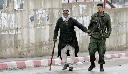 أحد عناصر الحرس الرّئاسي يساعد عجوزاً فلسطينياً لدى خروجه من صلاة الجمعة أمس (رويترز)