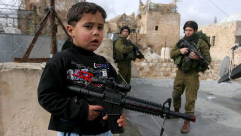 طفل فلسطيني يحمل رشّاشاً بلاستيكيّاً أثناء حملة تفتيش لجنود إسرائيليين في الجليل أمس(اي ب أي)