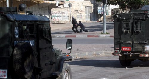 فلسطينيّة وابنها يركضان خلال المواجهات في نابلس أمس (إي بي أي)