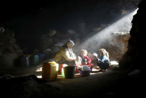 فلسطينيّة وطفليها في أحد كهوف غينيا فوق جنوبي بلدة الخليل (أرشيف - رويترز)