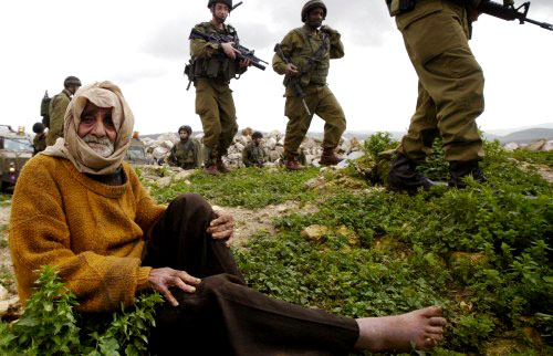 عجوز فلسطيني ينتظر أثناء قيام جنود إسرائيليّين بهدم منزله في يعبد قرب جنين أمس (رويترز)