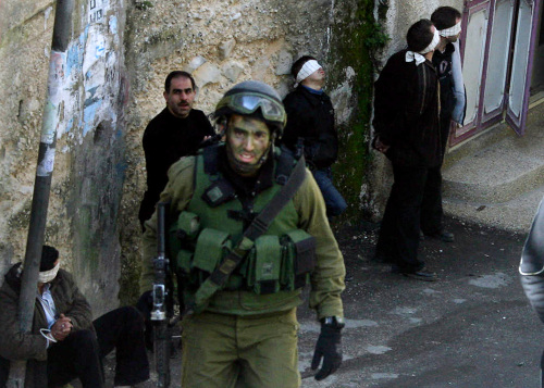 جندي إسرائيلي يحرس معتقلين فلسطينيّين في نابلس في الضفّة الغربيّة أمس (أ ف ب)