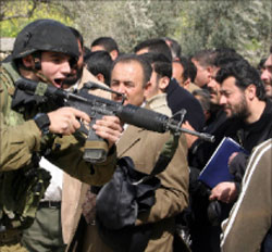 جندي يوجّه سلاحه نحو فلسطينيّين في نابلس أمس (أ ف ب)