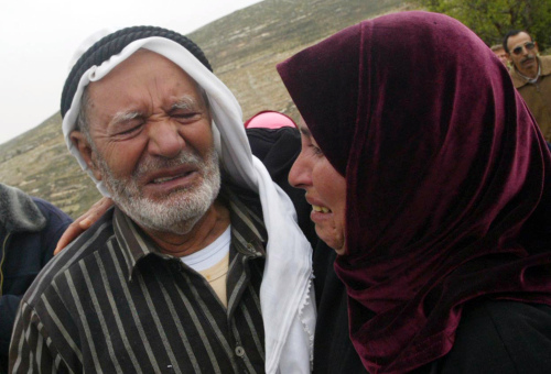 فلسطينيّة ووالدها يبكيان هدم الاحتلال لمنزلهما في حلحول قرب الخليل أمس  (أ ف ب)
