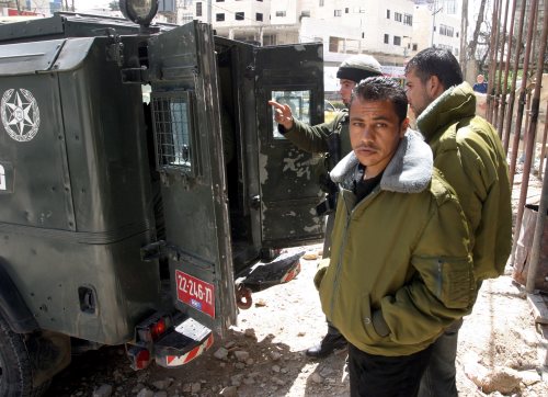 جنديّ إسرائيلي يقتاد معتقلين فلسطينيّين في الخليل أمس (إي بي أي)