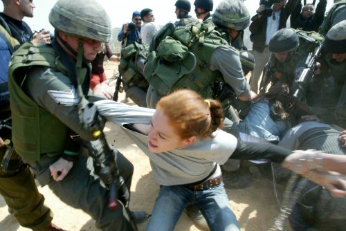 جندي الاحتلال يعتقل ناشطة خلال احتجاج ضدّ جدار الفصل في الضفّة الغربيّة أمس (موسى الشاعر - أ ف ب)