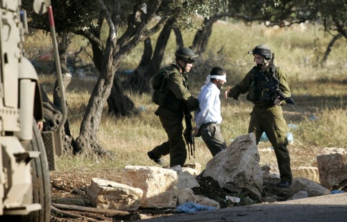 جنود إسرائيليون يعتقلون فلسطينياً في قباطية قرب جنين أمس (محمد تركمان - رويترز)