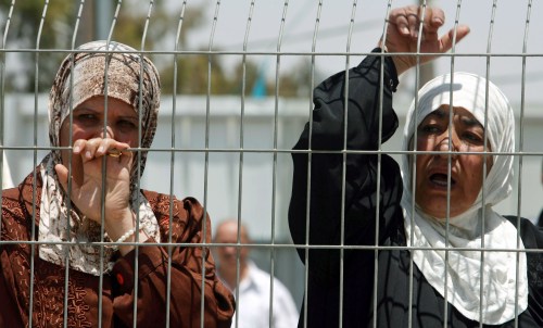 فلسطينيتان خلف سياج يفصلهما عن محكمة عسكرية قرب رام الله أمس (عامر عوض - رويترز)