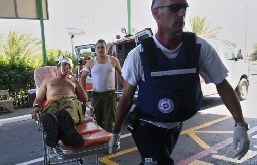 اسرائيليون يسعفون جندياً اصيب بصاروخ فلسطيني قرب غزّة أمس (تسافرير أبايوف - أ ب)
