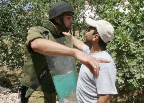فلسطيني يواجه جندياً إسرائيلياً في الضفة أمس (نايف هاشلامون - رويترز)