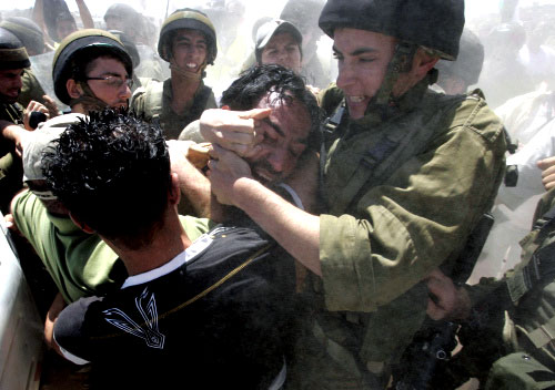 جنود اسرائيلون يعتدون على فلسطيني ضد جدار الفصل في الضفة الغربية أمس (موسى الشاير - أ ف ب )