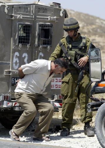 جندي إسرائيلي يعتقل فلسطينياً قرب بيت لحم أمس (موسى الساهر - أ ف ب)