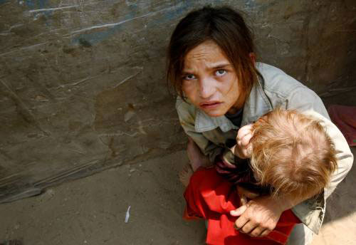 فتاة تحتمي مع طفل في بيت لاهيا خلال التوغّل الاسرائيلي أمس (سهيب سالم - رويترز)