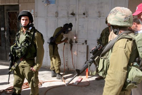 جنود اسرائيليون بالقرب عامل فلسطيني في الخليل أمس (عبد الحفيظ هشلمون - إي بي أي)