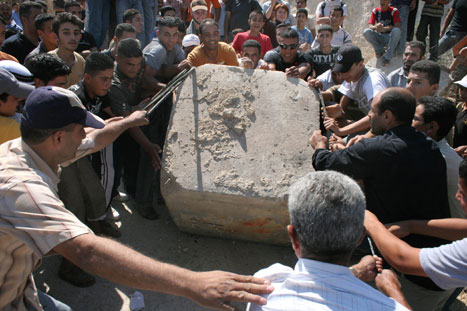 فلسطينيون يزيلون حجرأً كبيرأً خلال تظاهرة ضد الحواجز الإسرائيلية بالقرب من نابلس أمس (سترينغر - رويترز)