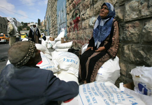 فلسطينية تراقب تسليم مساعدات من الأونروا في الخليل أمس (حازم بدر - أ ف ب)
