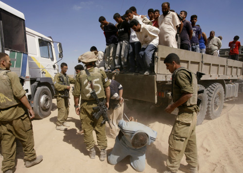 جنود إسرائيليون يعتقلون فلسطينيّين في غزة أمس (متي ميل رود - أ ب)