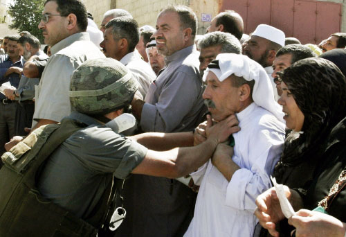 جندي إسرائيلي يؤنب فلسطينياً خلال اجتيازه نقطة تفتيش للوصول الى القدس المحتلة (ناصر شيوخي  - أ ب)