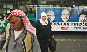 فلسطينيّان أمام حافلة عليها صورة للسيّد حسن  نصر الله وبوش وهنيّة في القدس المحتلّة أمس (محمّد محيسن ـ أ ب)