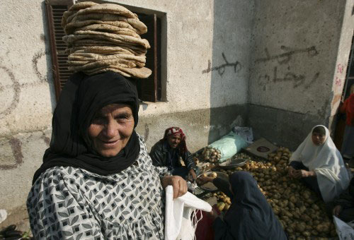 مصريّة تضع أرغفة الخبز التي تمكّنت من شرائها على رأسها في محافظة الشرقيّة (ناصر ناصر ـ أ ب)