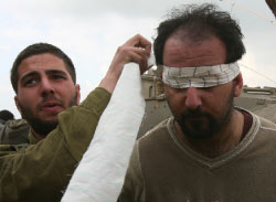 جندي إسرائيلي يعصب عينيْ فلسطينيّ اعتقله في غزّة أول من أمس (مناحيم كاهانا ـ أ ف ب)