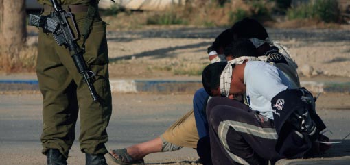 جندي إسرائيلي بالقرب من معتقلَين فلسطينيَّين على الحدود بين غزّة والأراضي المحتلّة أمس (تسافرير أبايوف ـــ