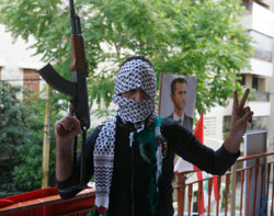 مسلّح يرفع شارة النصر وخلفه صورة لبشّار الأسد في مكتب لتيّار المستقبل في رأس النبع أمس (محمّد عزاقير ـــ رويترز)