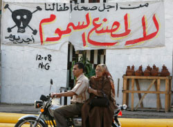 مصريّان يمرّان أمام لافتة مناهضة لإنشاء مصنع الأسمدة الزراعيّة في دمياط أول من أمس (أسماء وجيه ـــ رويترز)