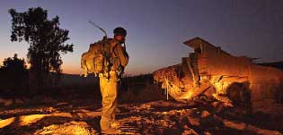 جندي إسرائيلي يستعد لركوب آلية في شمال إسرائيل للدخول إلى لبنان أمس (رويترز)