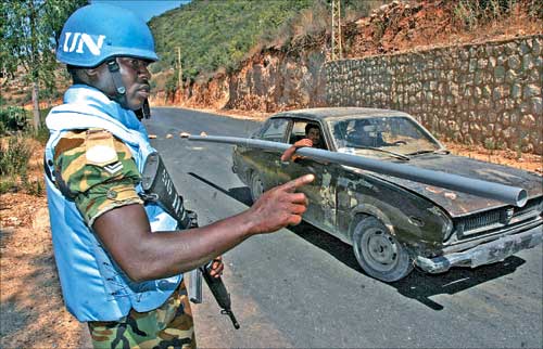 جندي من القوة الدولية العاملة في الجنوب يأذن لسيارة مدنية بالمرور